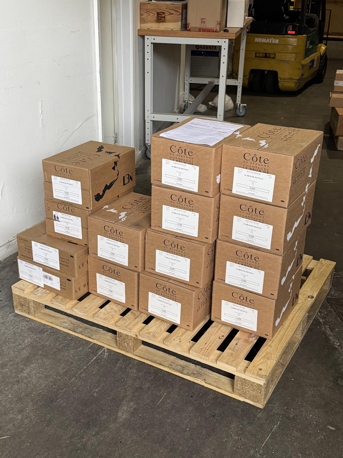 Cases of Le Brun de Neuville Côte de Sézanne Champagne stacked on a wooden pallet ahead of restocking.