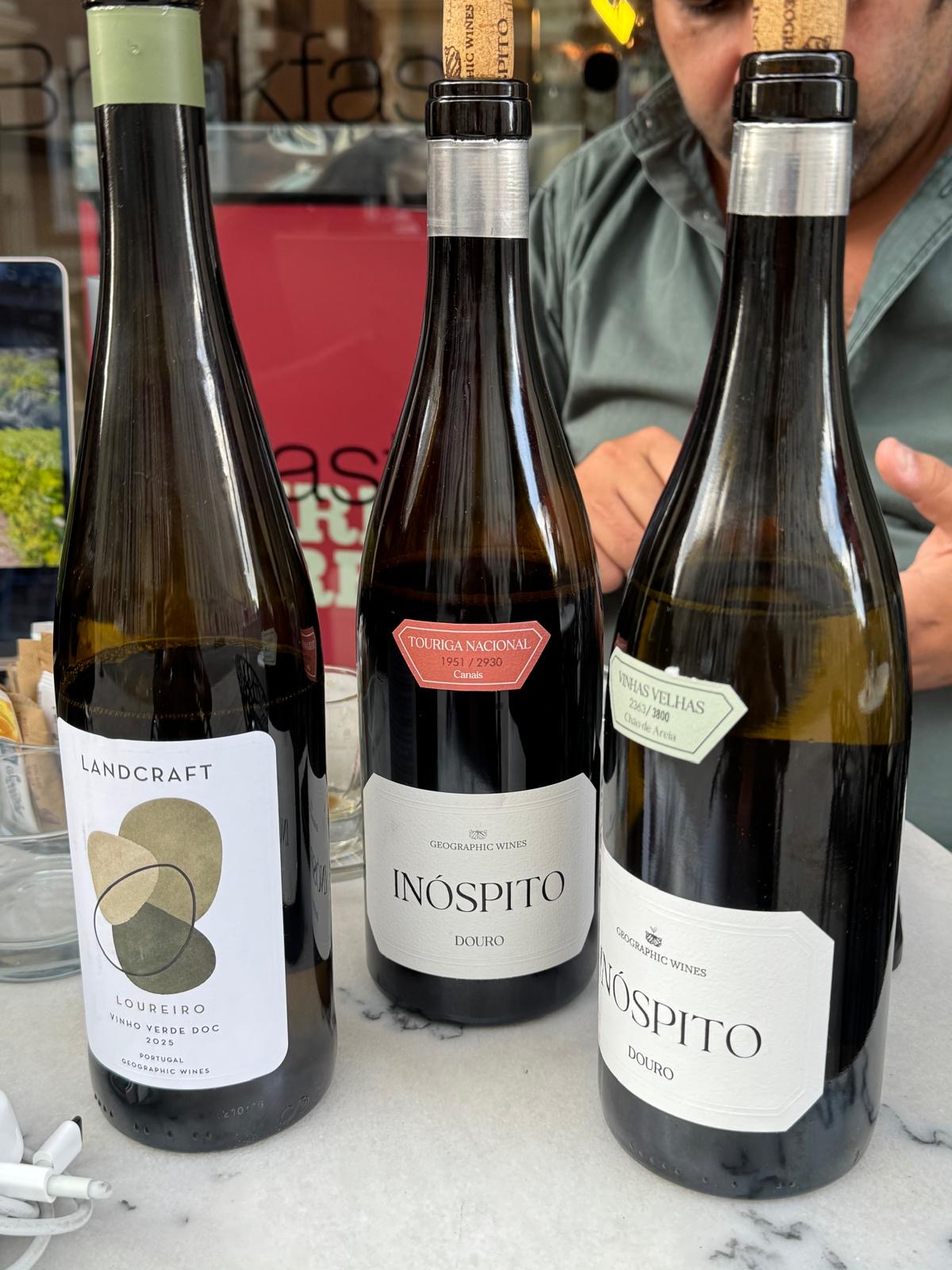 Three bottles from Geographic Wines on a marble table: a Loureiro Vinho Verde and two Douro wines from the Inóspito range.